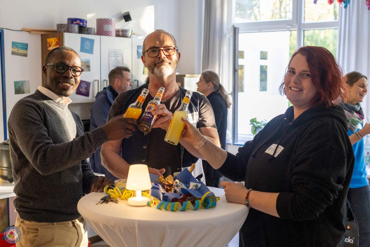 Drei fröhliche Menschen stoßen mit alkoholfreien Getränken an.